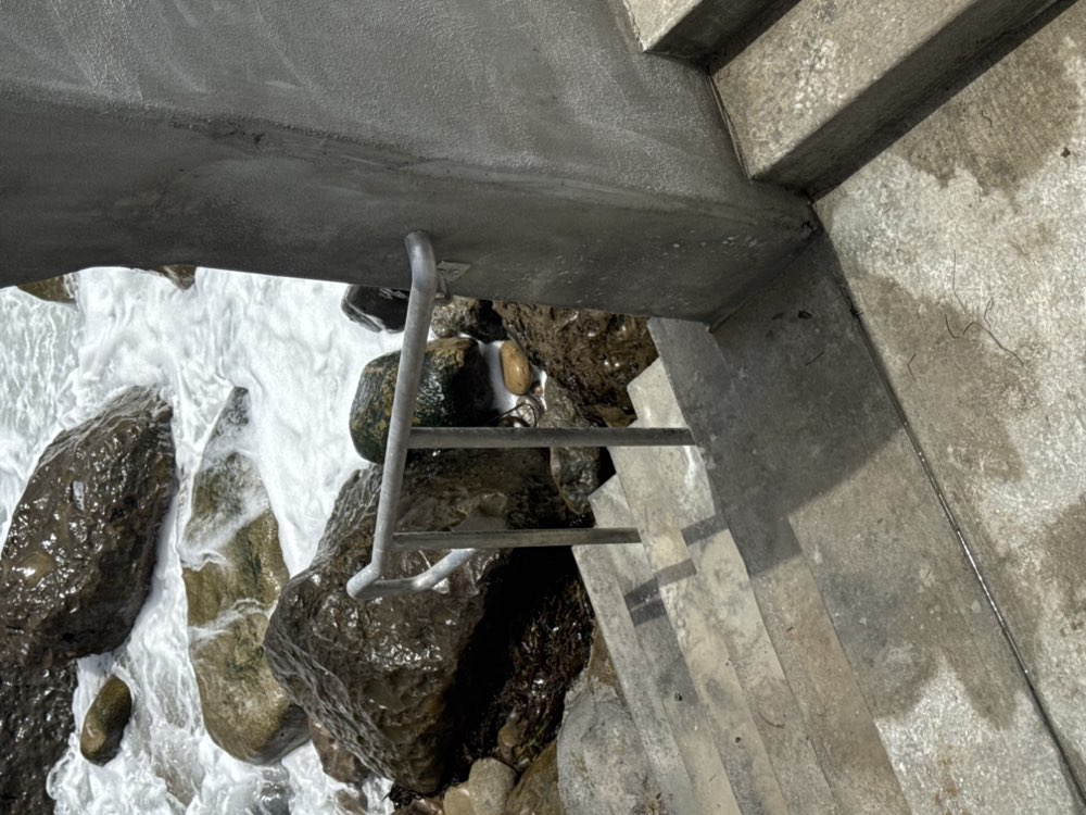 Stainless steel oceanfront ladder and railing on coastal rocks by Legendary Metal Works