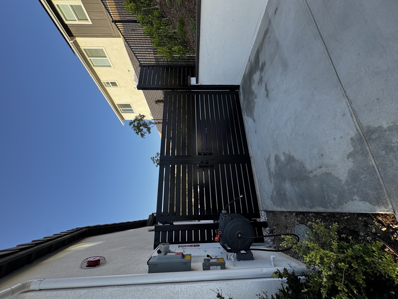 Black horizontal slat fence panel and matching gate on a sloped residential lot