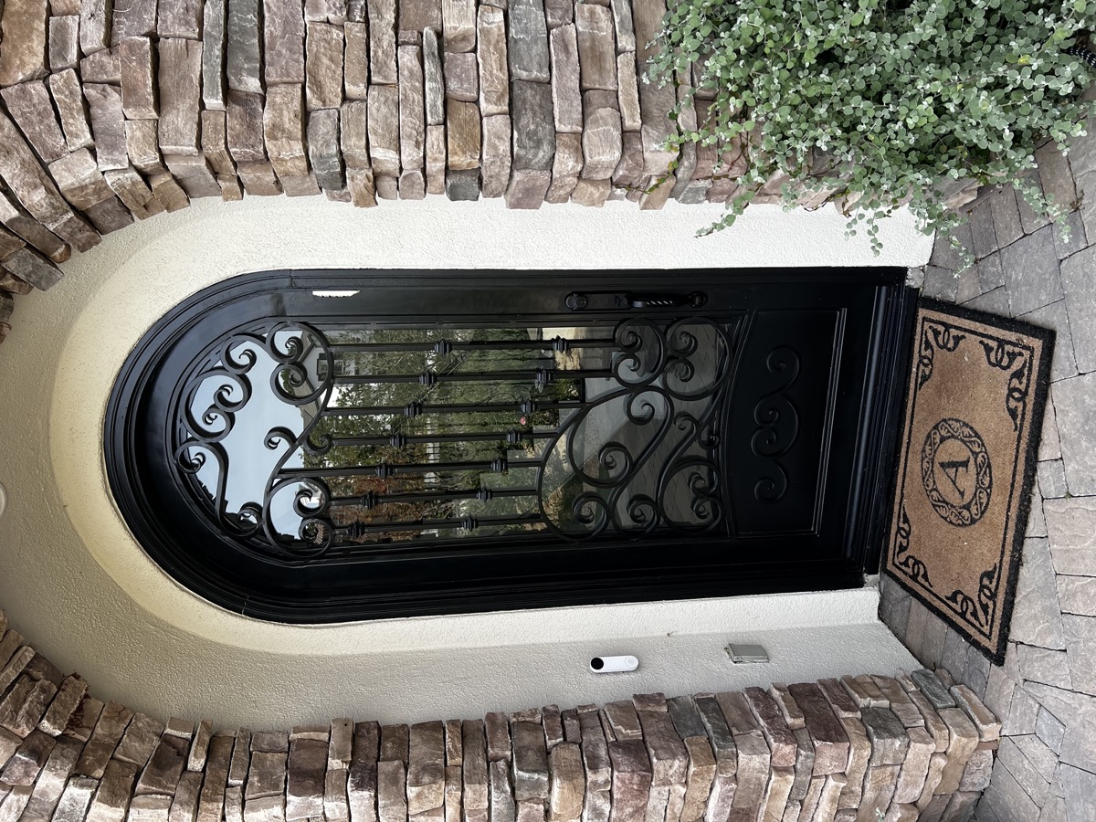 Custom ornamental iron front door with stone archway in Ventura County
