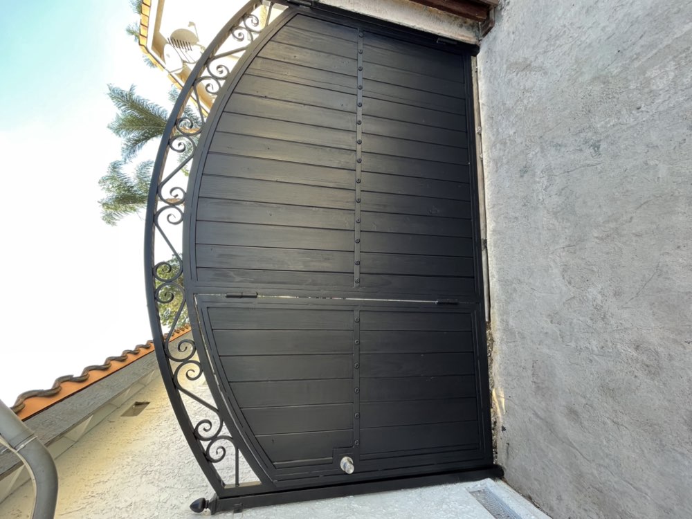 Arched ornamental gate with horizontal slats and scrollwork by Legendary Metal Works
