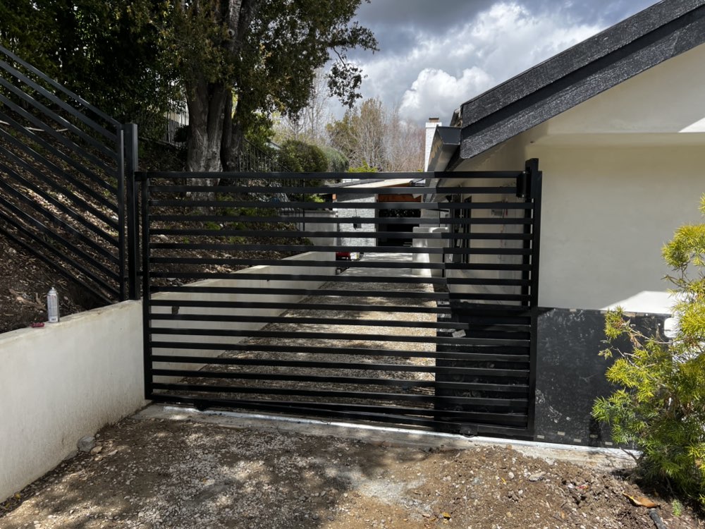 Modern horizontal slat sliding gate with matching fence by Legendary Metal Works