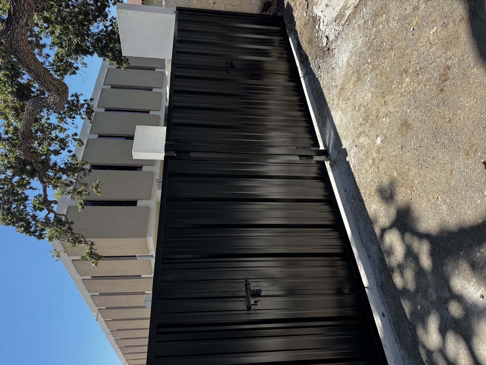 Black horizontal slat privacy driveway gate with matching slat fencing