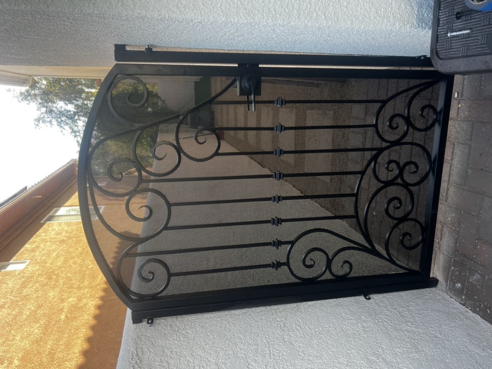 Ornamental wrought iron gate with scrollwork and glass panels by Legendary Metal Works